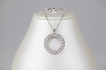 A mid-luxury diamond necklace featuring a circular motif encrusted with pavé diamonds, blending symbolic form (circle = eternity) with sparkle. Great entry-level luxury statement piece.